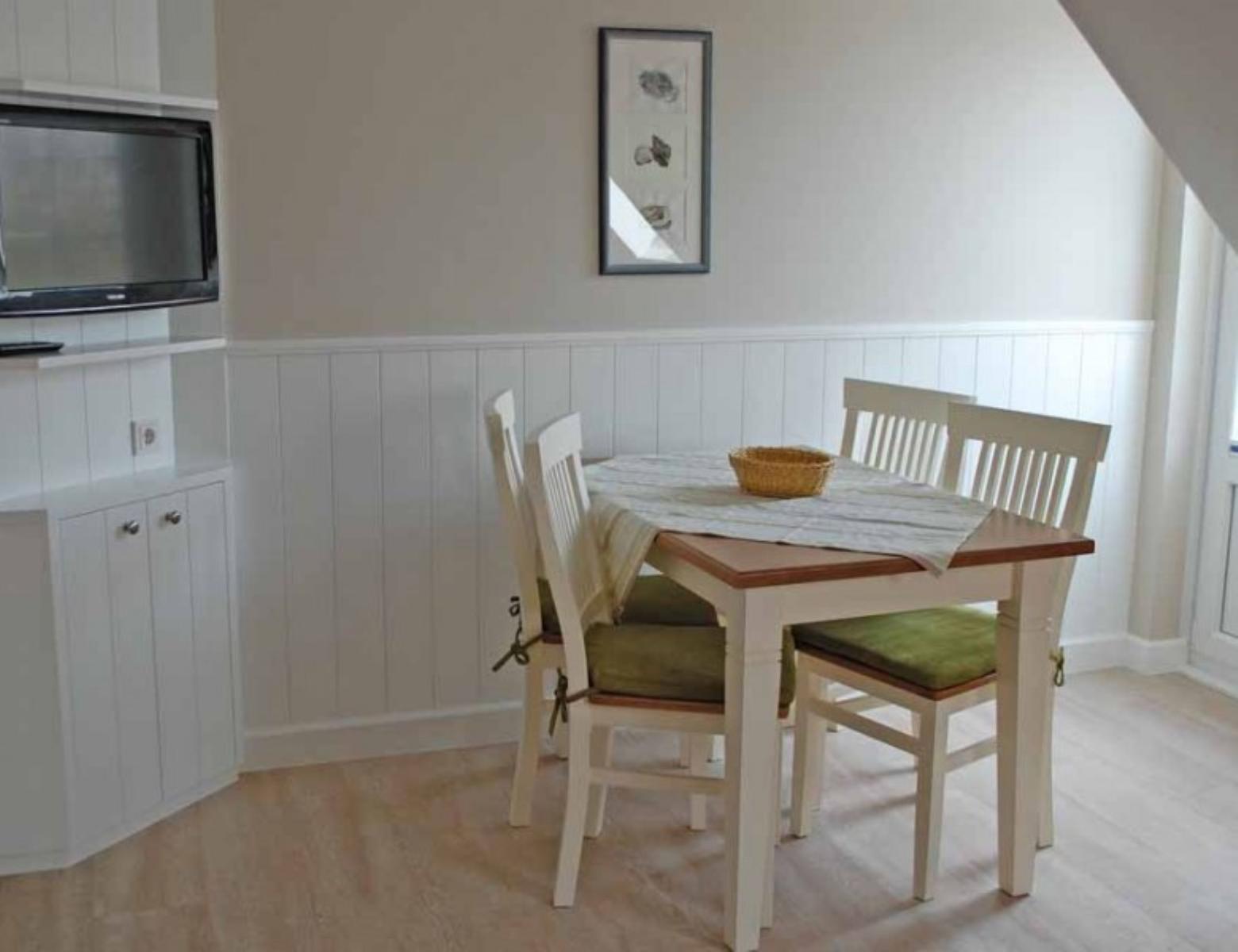 Dining area with table, four chairs, and TV mounted on the wall.
