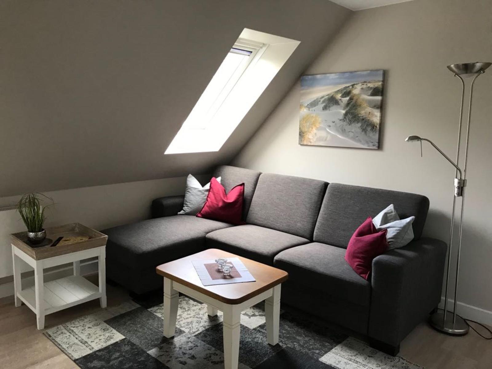 A living room with gray sofa, wooden table, and skylight.