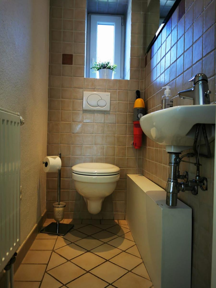 Badezimmer mit Toilette, Waschbecken und Fenster
