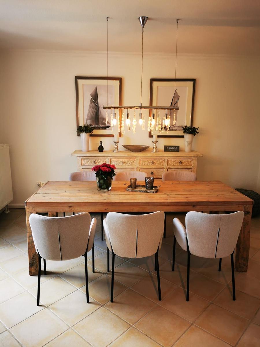 Holztisch mit Stühlen, Deckenleuchte und Wandbildern im Esszimmer.