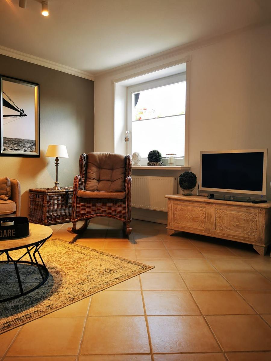 Wohnzimmer mit Sessel, Fernseher und Fenster