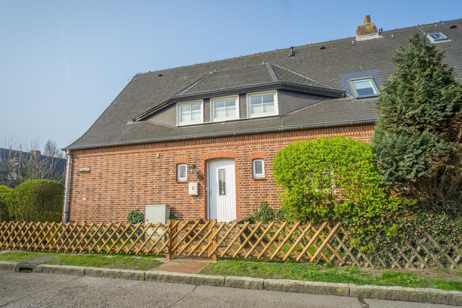 Red brick house with white windows and wooden fence.