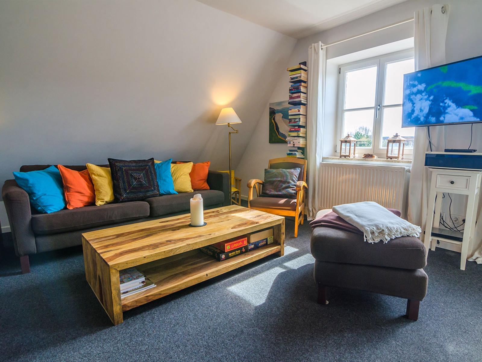 Living room with sofa, coffee table, and TV mounted on the wall.