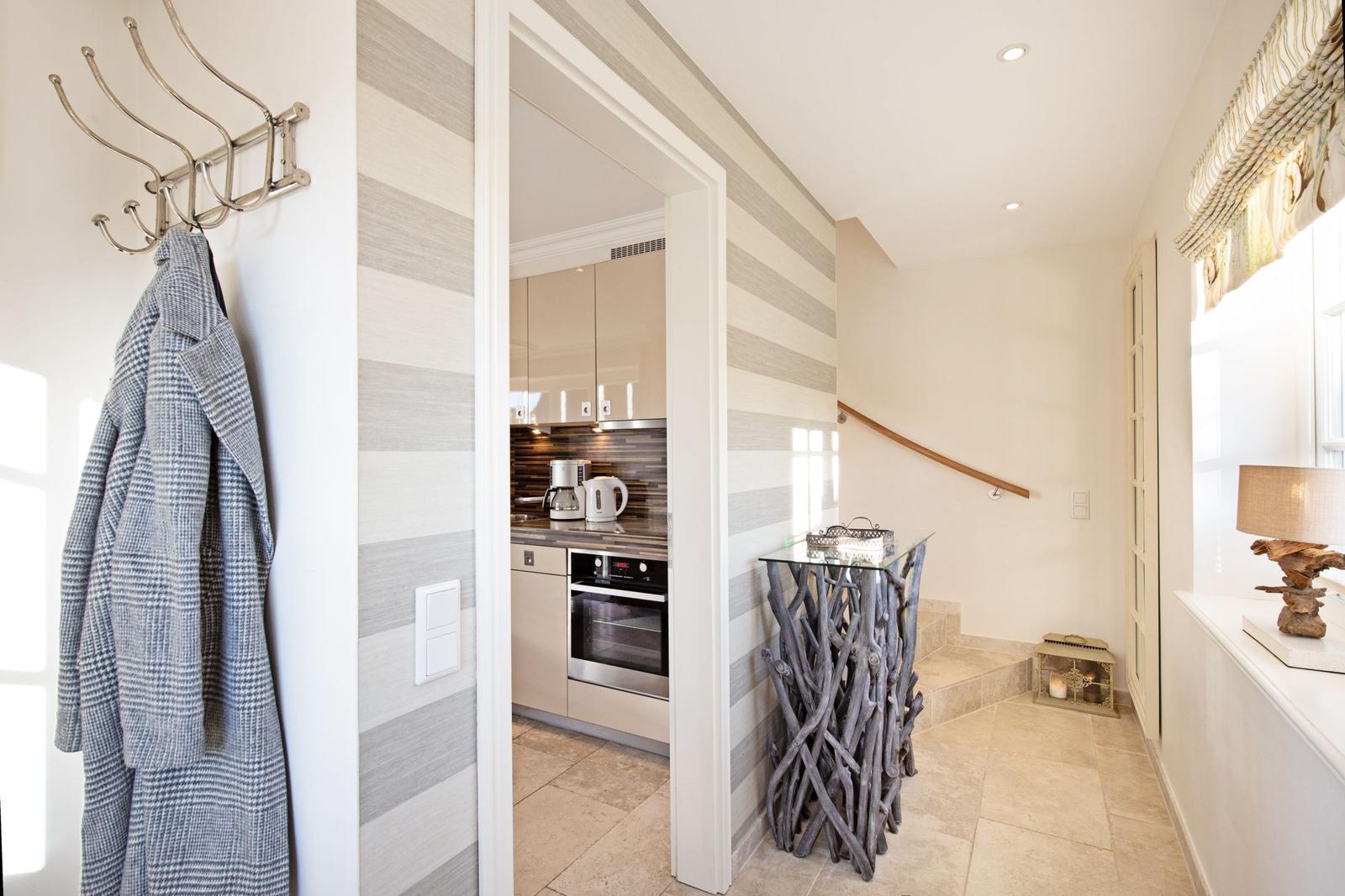 Entrance with coat rack, kitchen area, and staircase