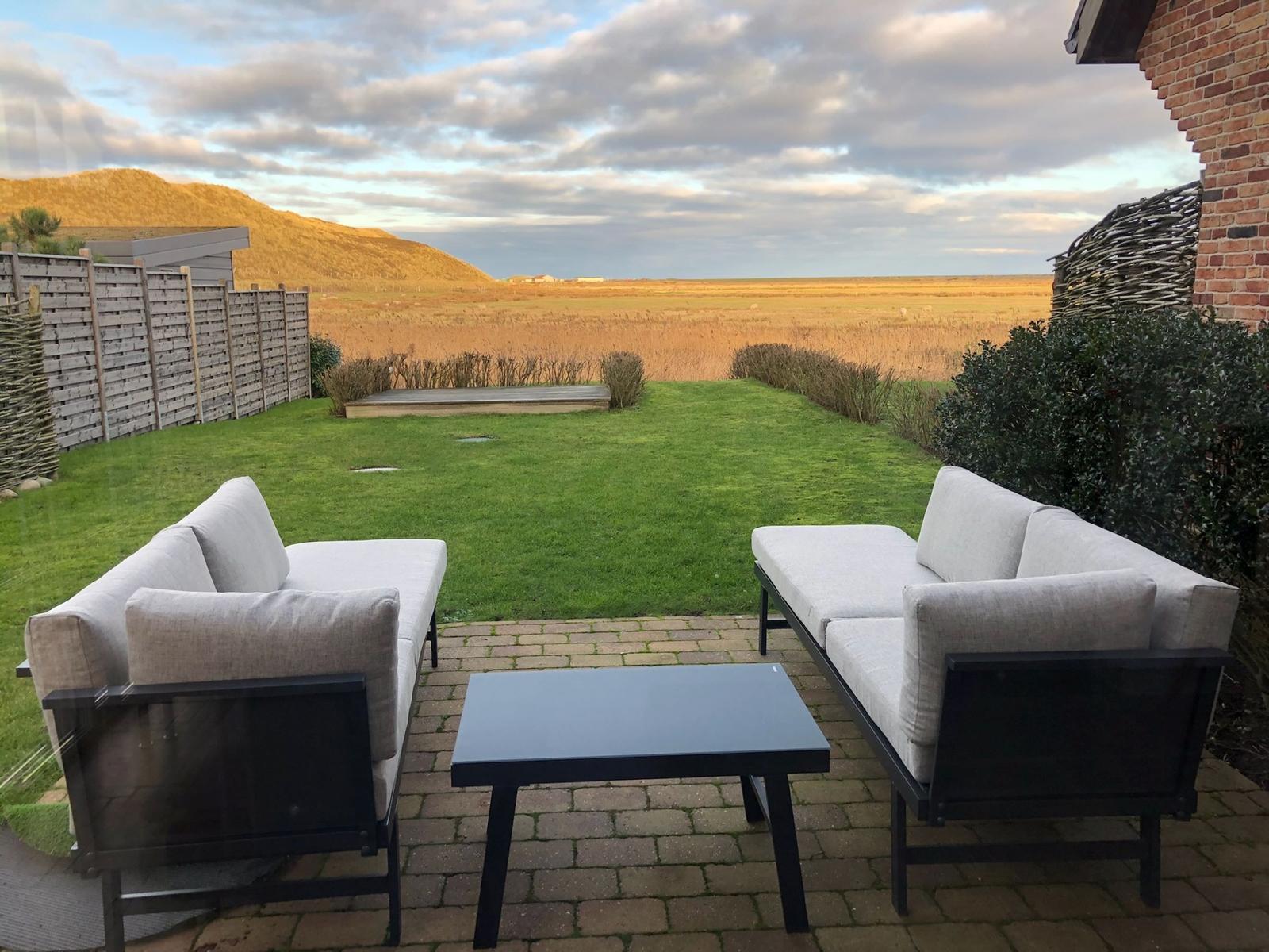 Terrace with two sofas and table. View of lawn and hills.