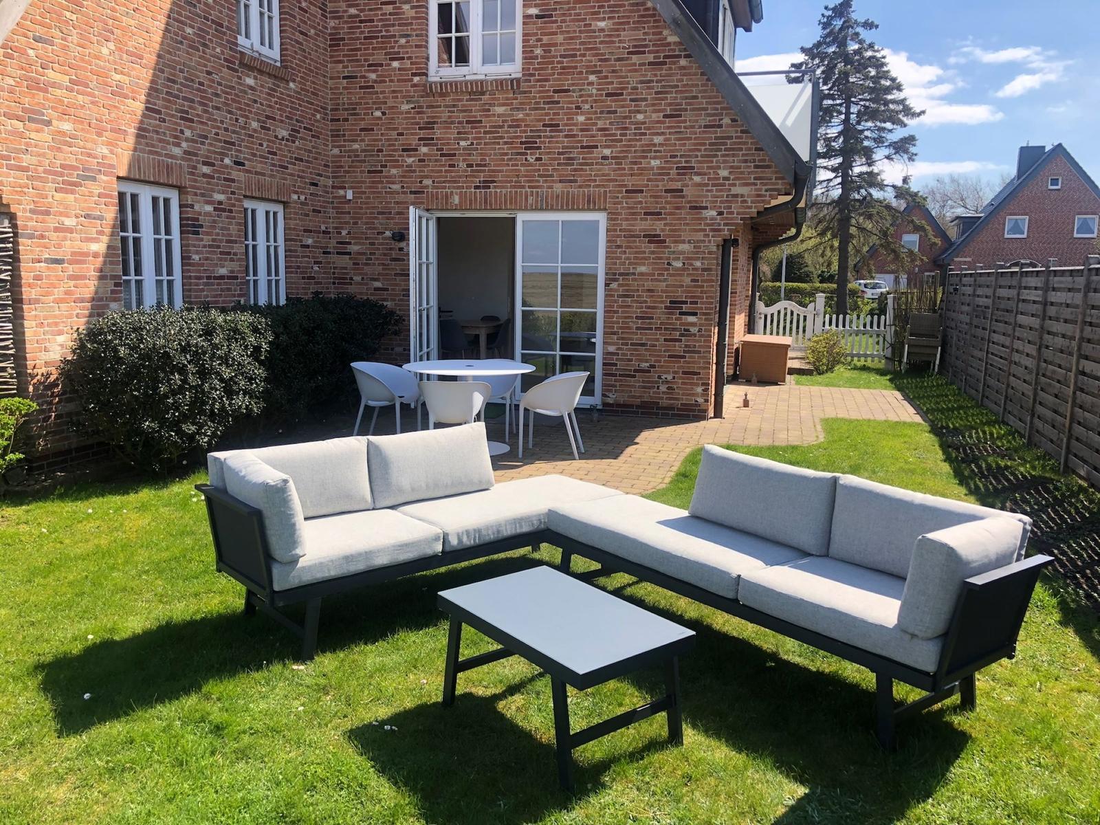 Backyard with garden furniture and terrace in front of brick house