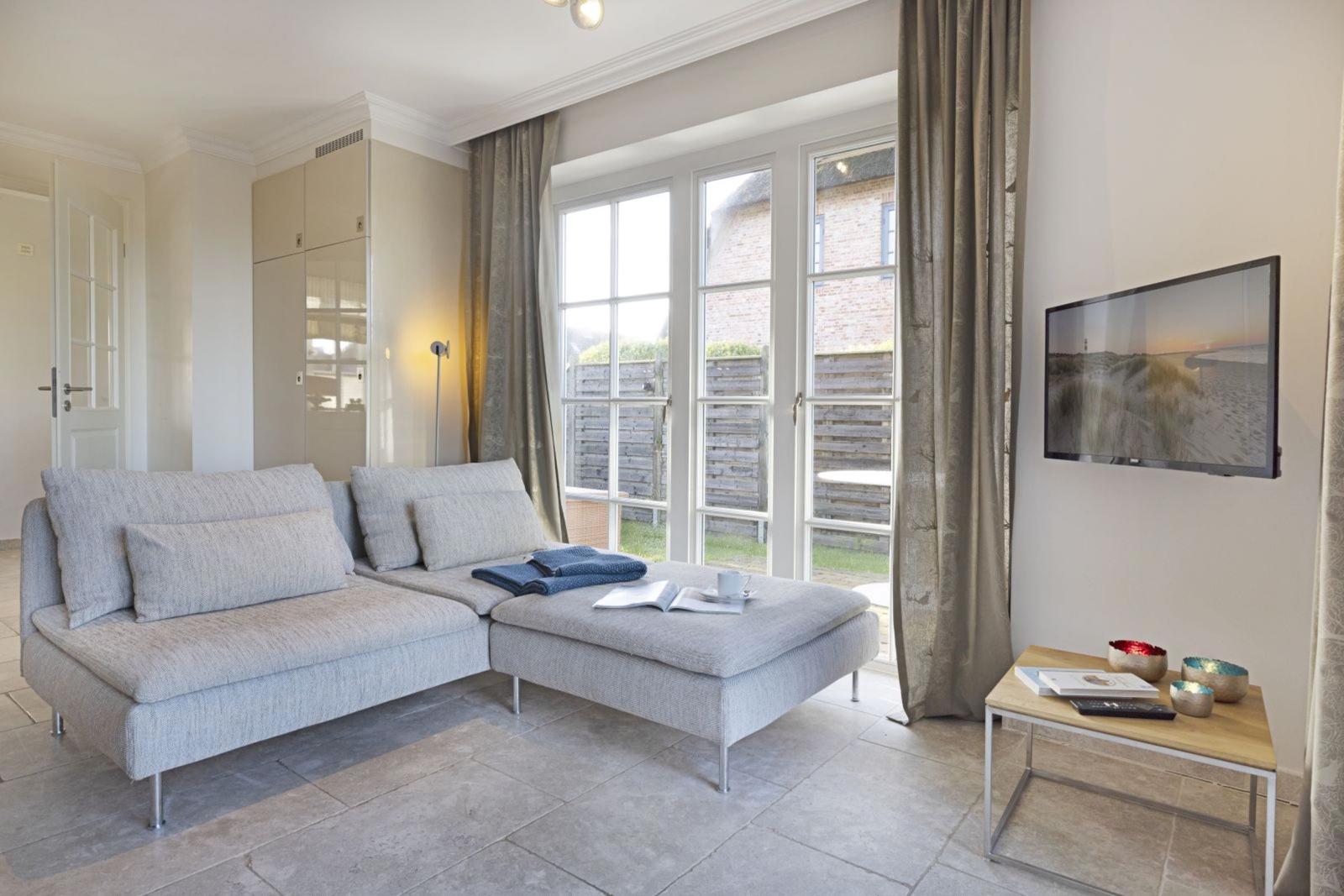 Living room with sofa, TV, and window to outdoor terrace.