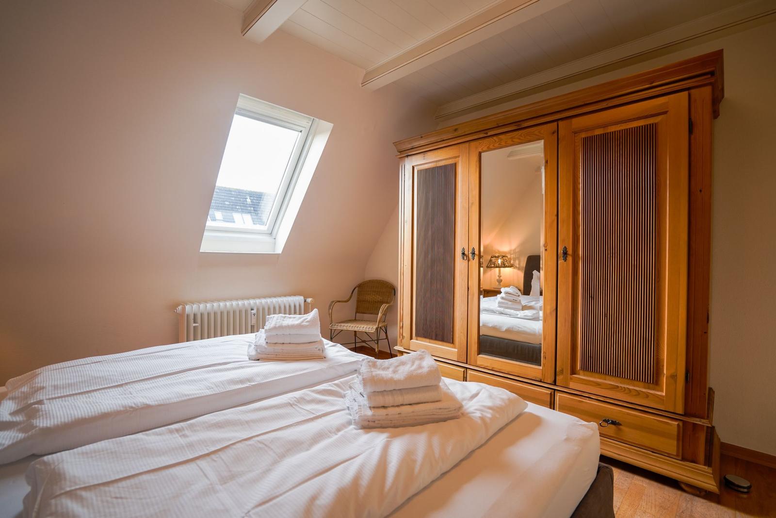 Bedroom with sloped ceiling, double bed, wooden wardrobe, and skylight.