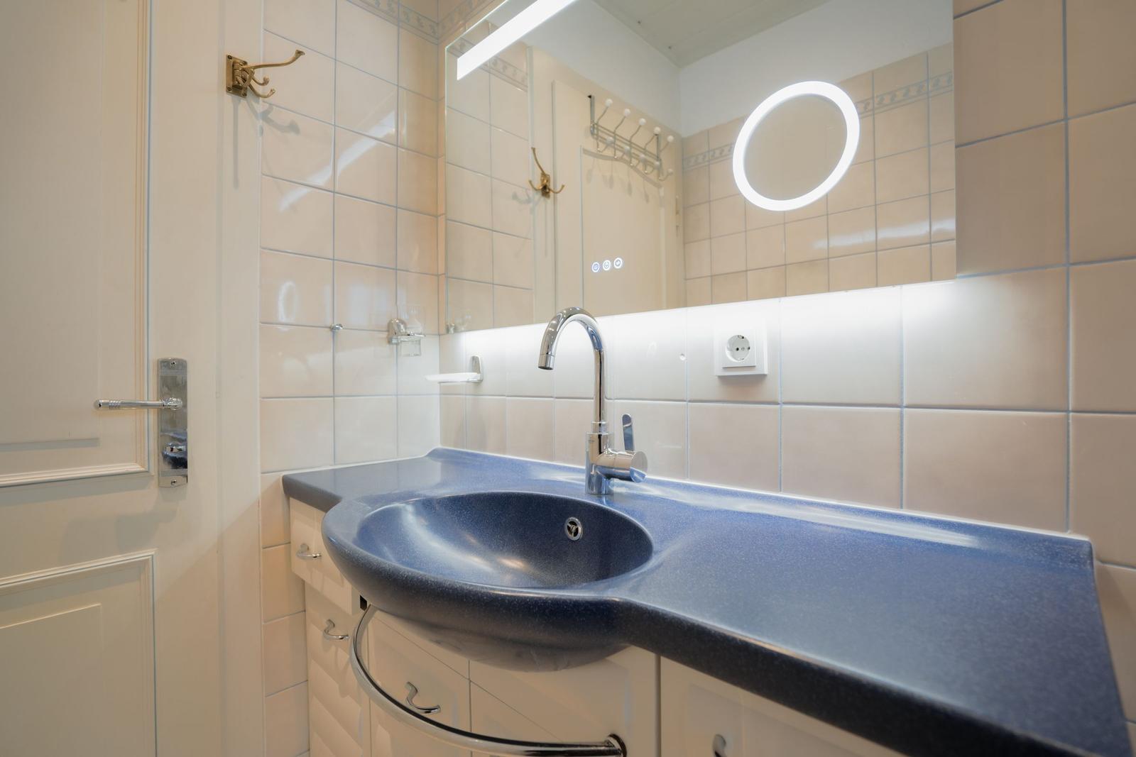 Bathroom with blue sink and illuminated mirror