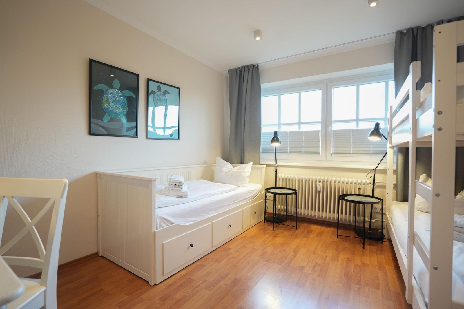 Room with double bed, bunk bed, window, and wall art.