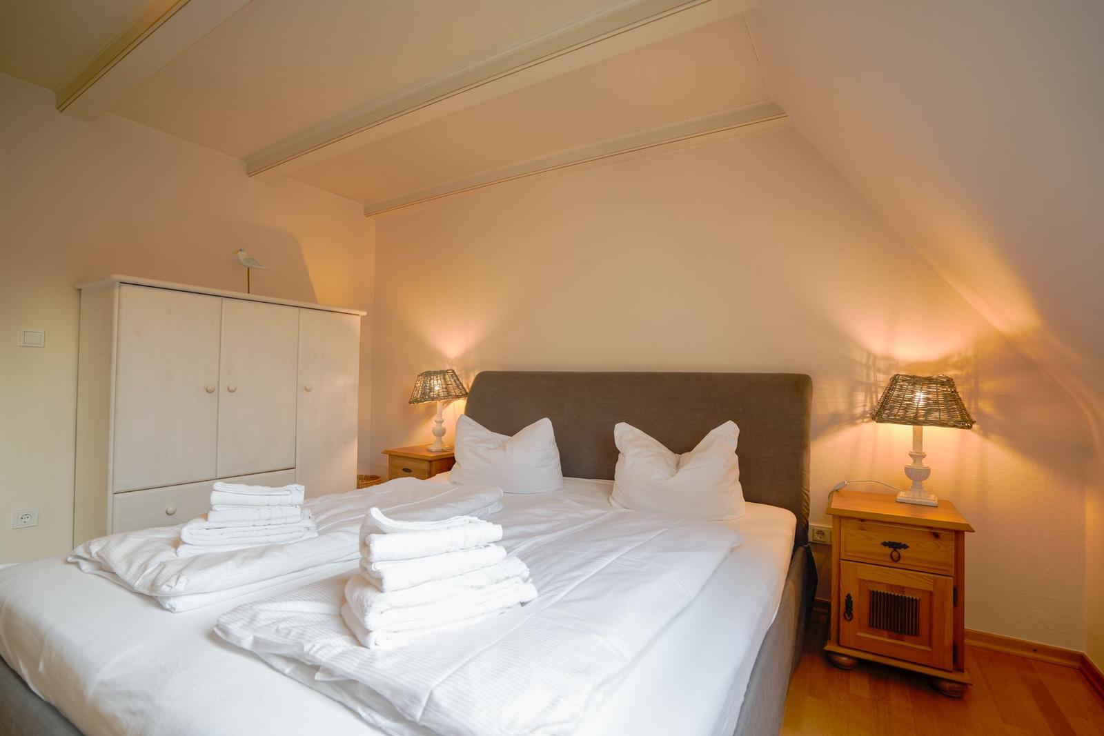 Bedroom with double bed, two nightstands, and wardrobe under sloped ceiling.