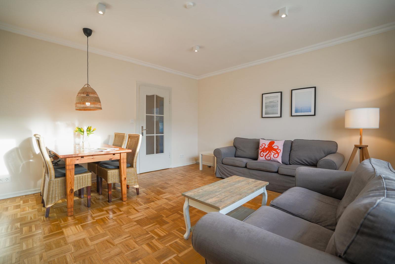 Living and dining area with sofa, dining table, and wooden floor.