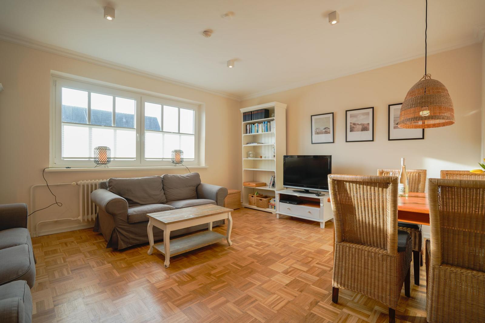 Living and dining area with sofa, TV, dining table, and bookshelf.