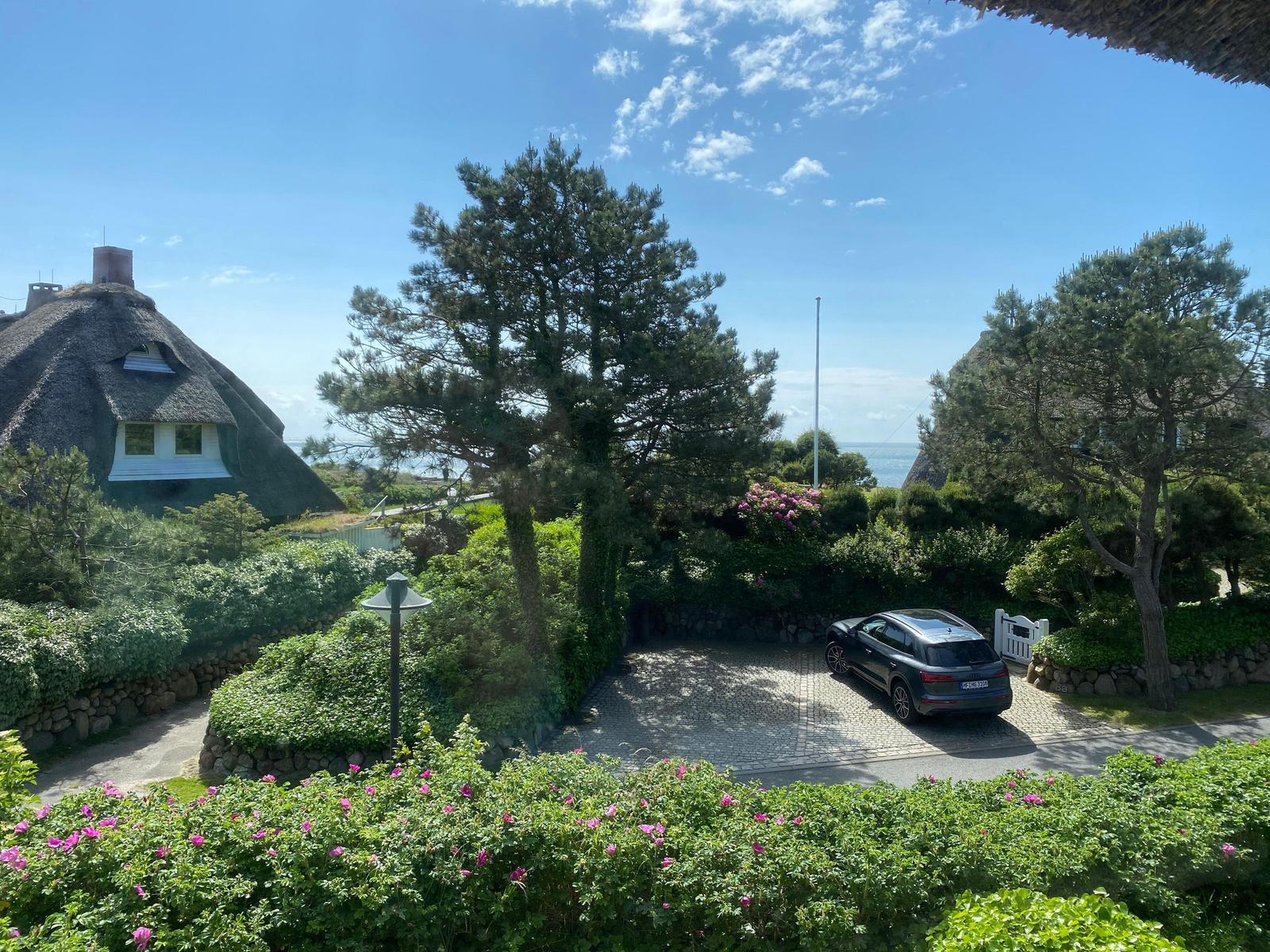 Thatched house with garden, car parked, sea view.