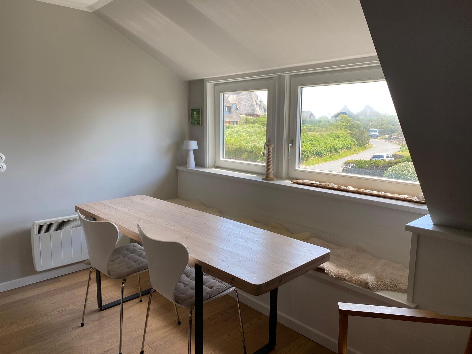 Essbereich mit Tisch und Stühlen. Fensterblick auf grüne Landschaft.