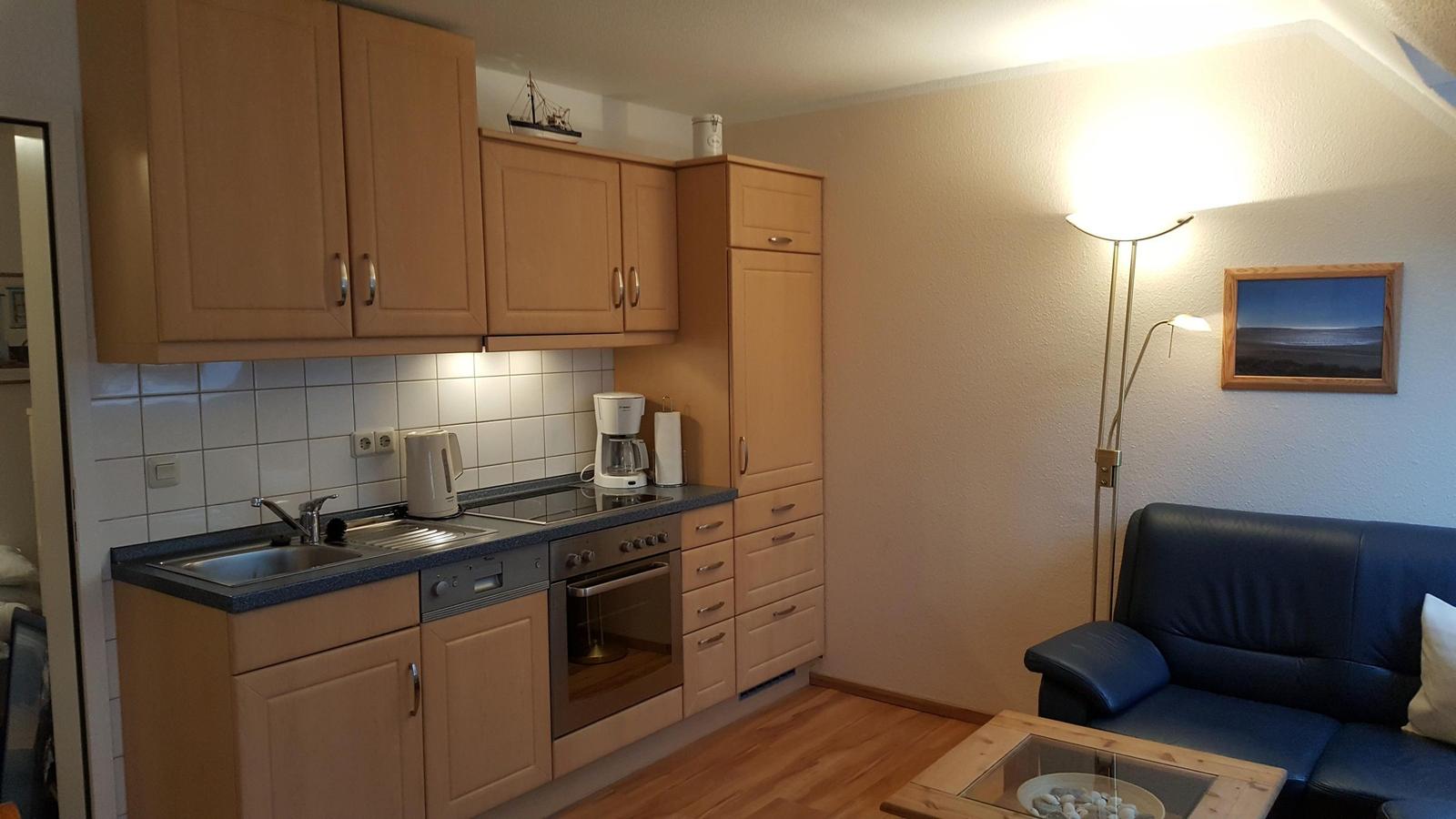 Kitchen with wooden cabinets and living area with sofa and floor lamp.