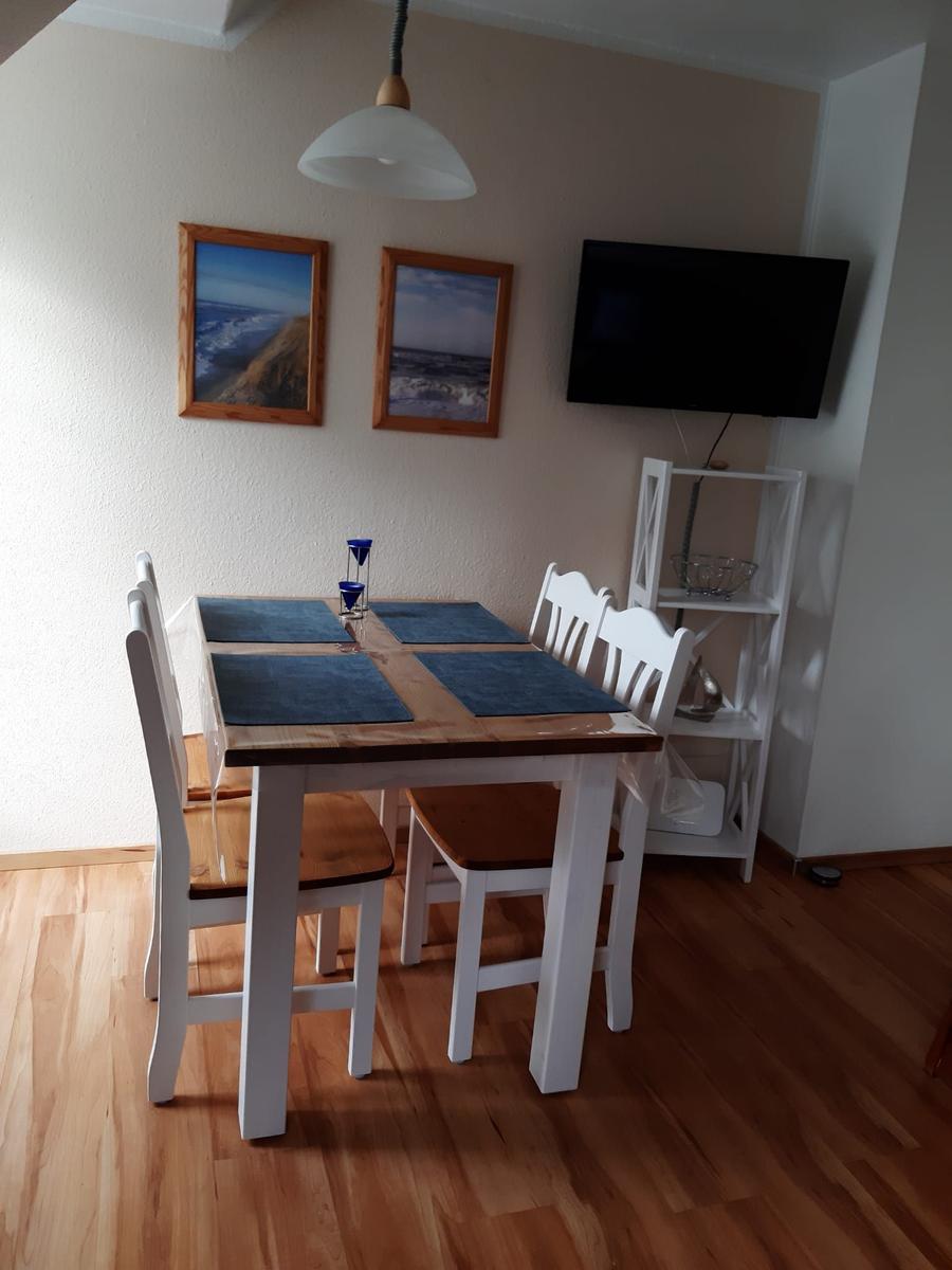 Dining area with table, chairs, and wall pictures. TV mounted on the wall.