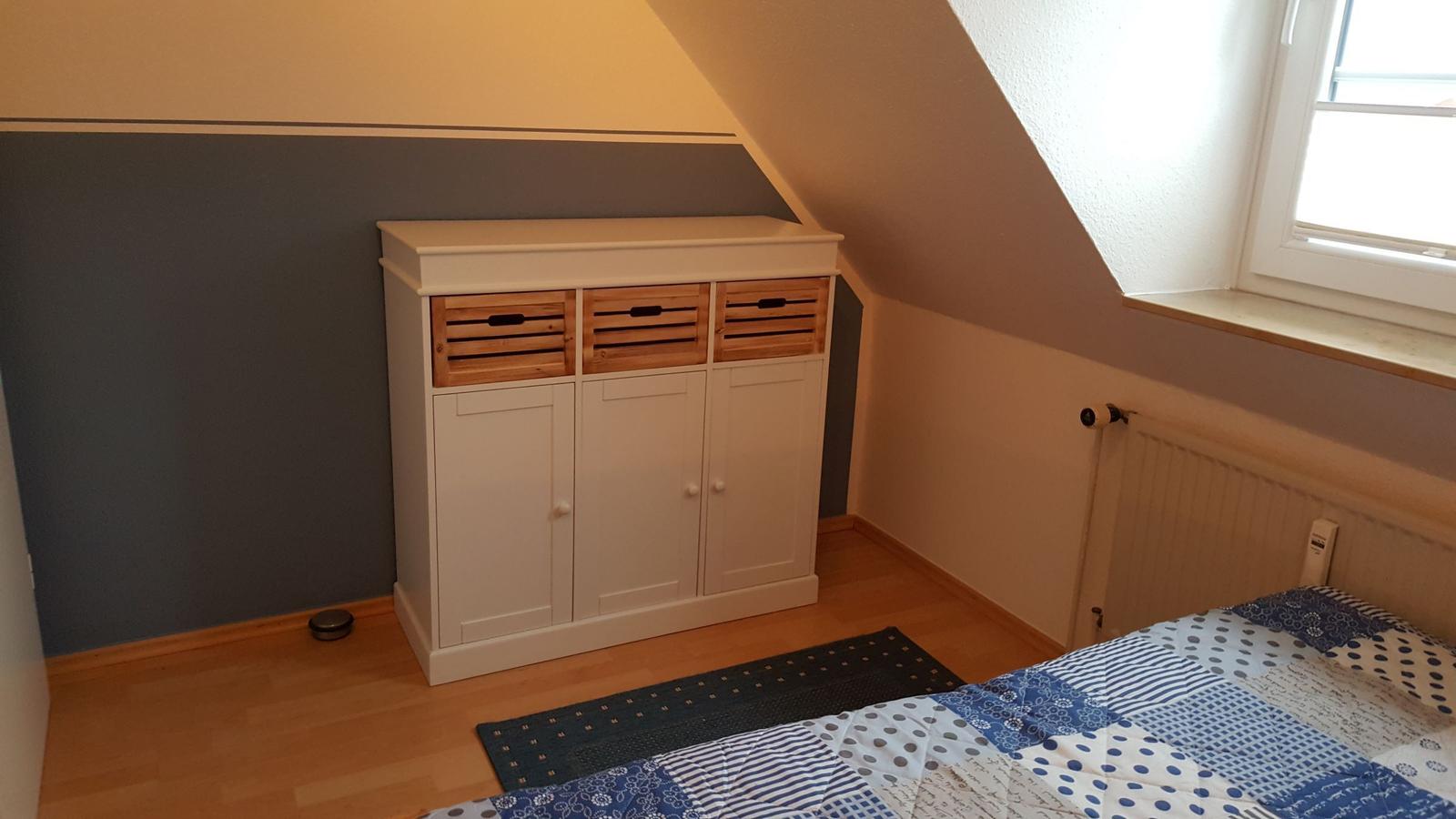 Bedroom with sloped ceiling, wardrobe, and bed.