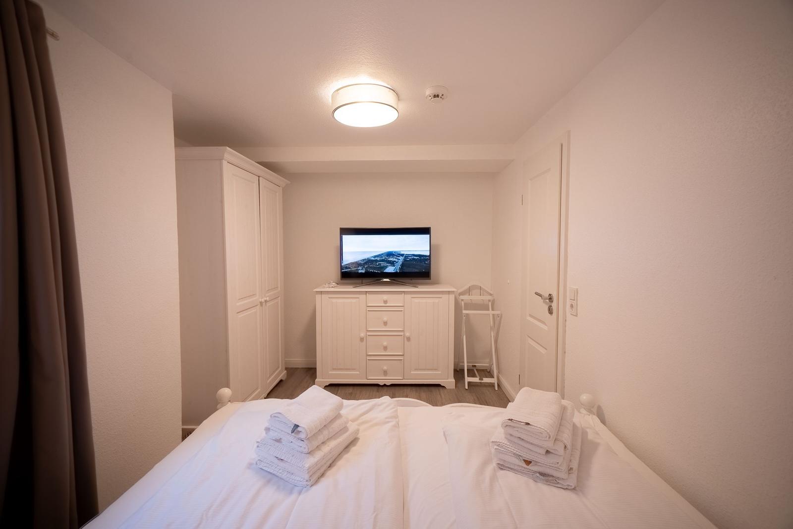 Schlafzimmer mit Bett, TV und Kleiderschrank.