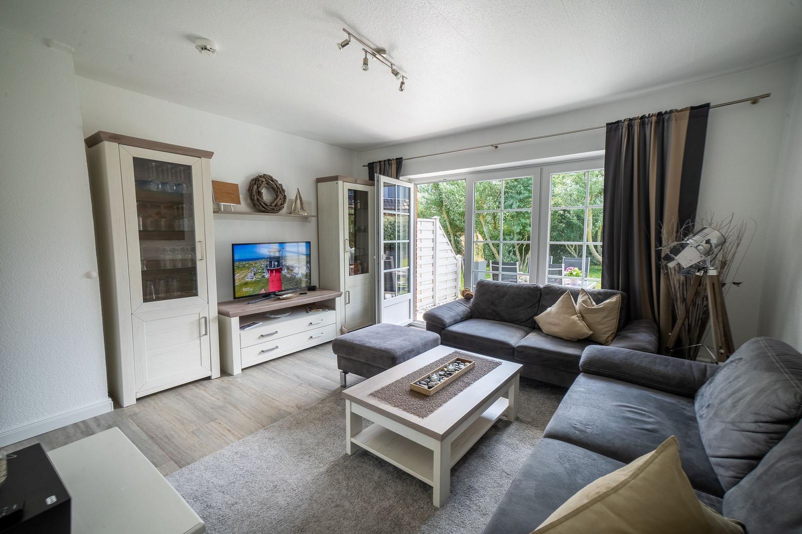 Wohnzimmer mit Sofa, Fernseher und Terrassentür.