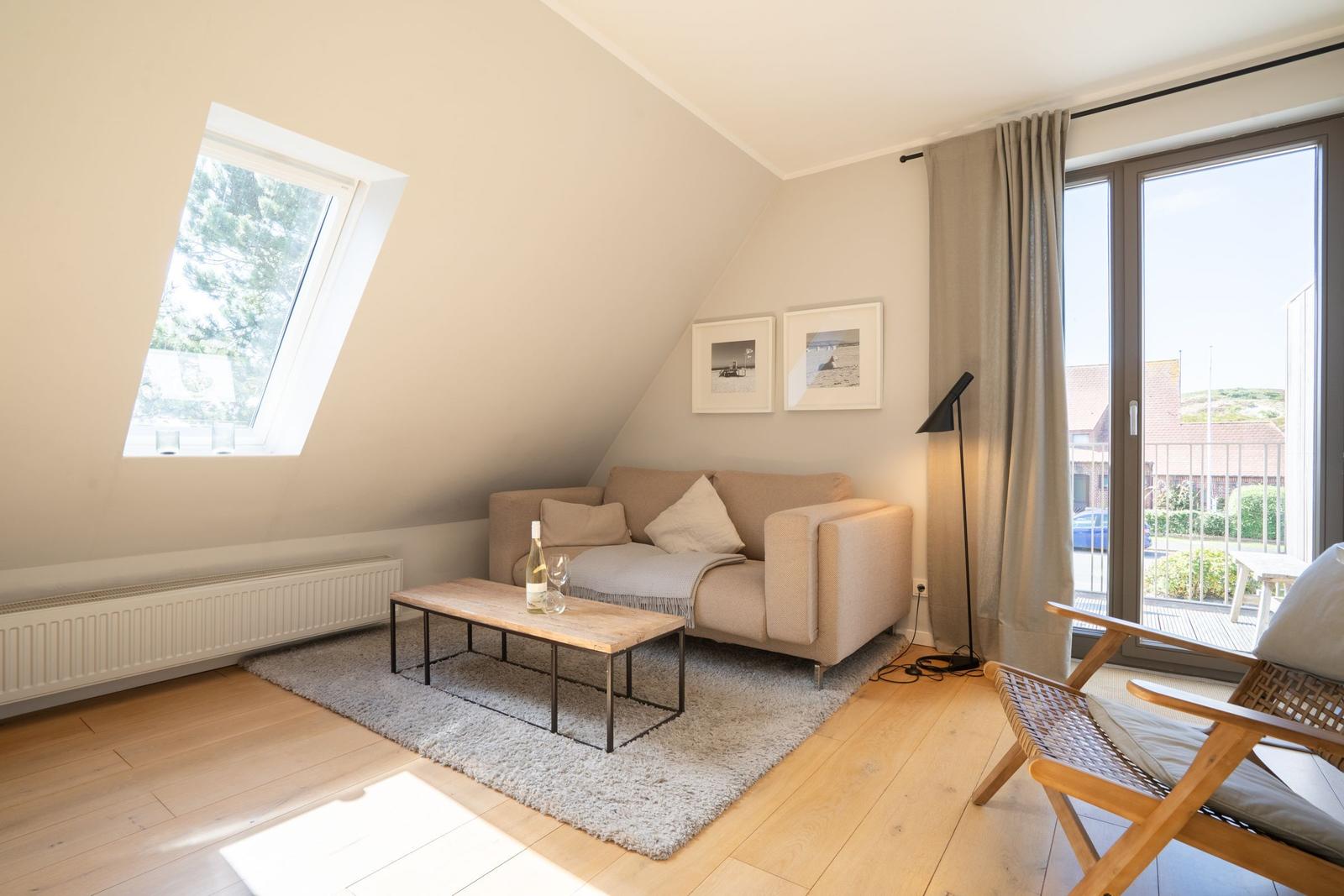 Living room with sofa, coffee table, and view of balcony.