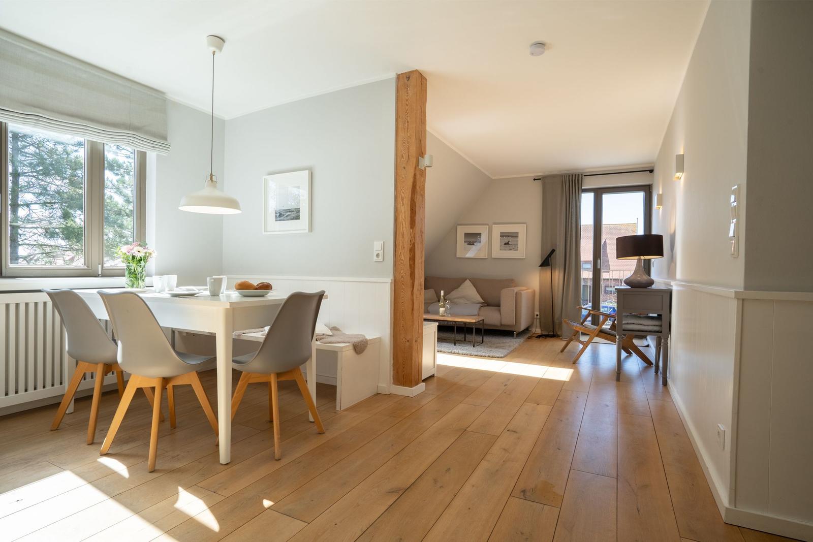Dining area with table and chairs, living room with sofa and windows