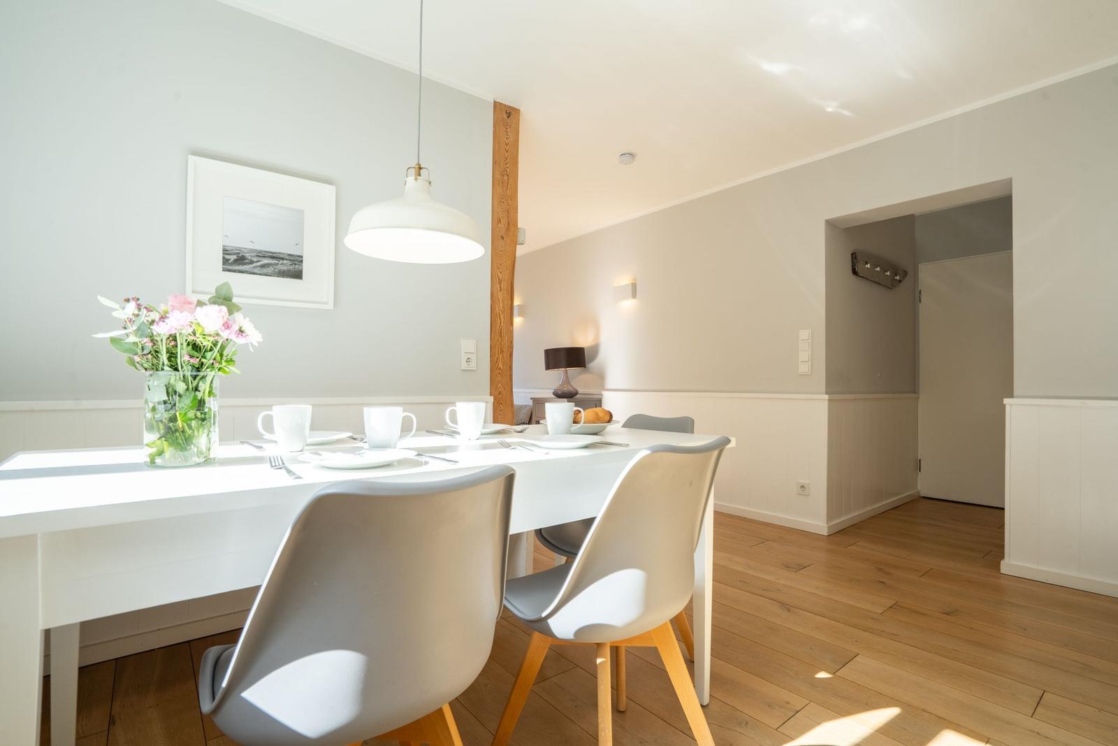 Dining area with white table, gray chairs, and floral arrangement.