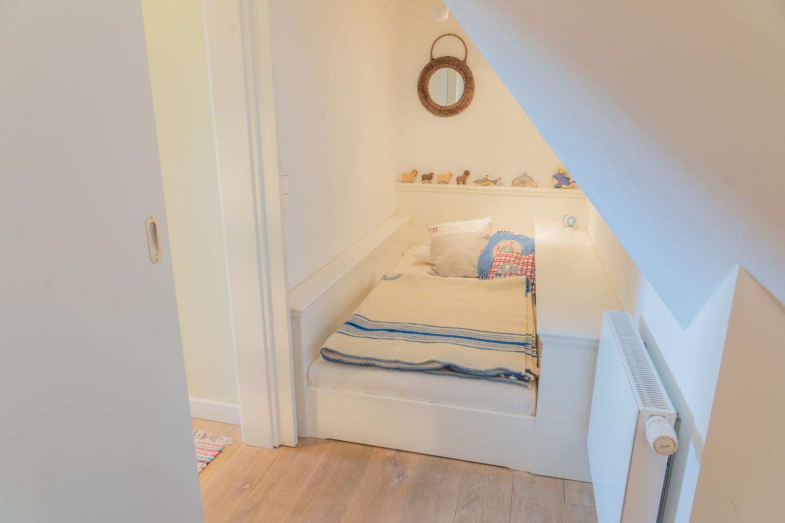 Schlafzimmer mit Dachschrägen, Bett und Wandspiegel