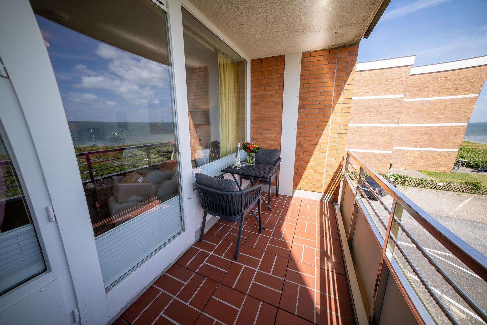 Terrace with table, two chairs, and sea view.