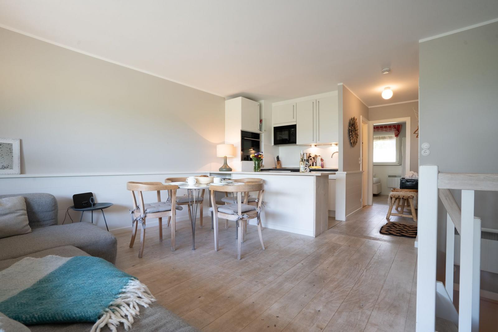 Wohn- und Küchenbereich mit Esstisch, Sofa und Holzboden.