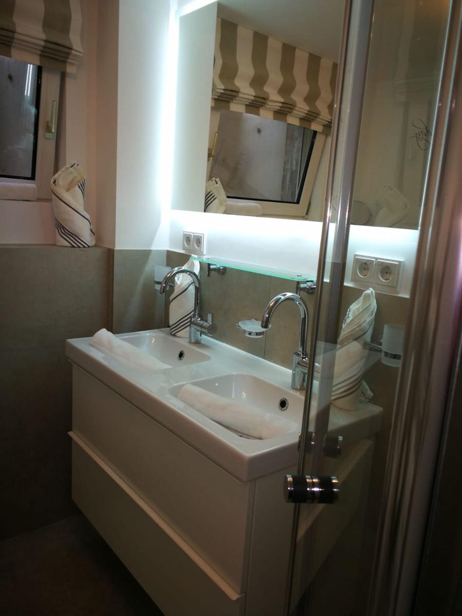 Badezimmer mit Doppelwaschbecken, Spiegel und Dusche.