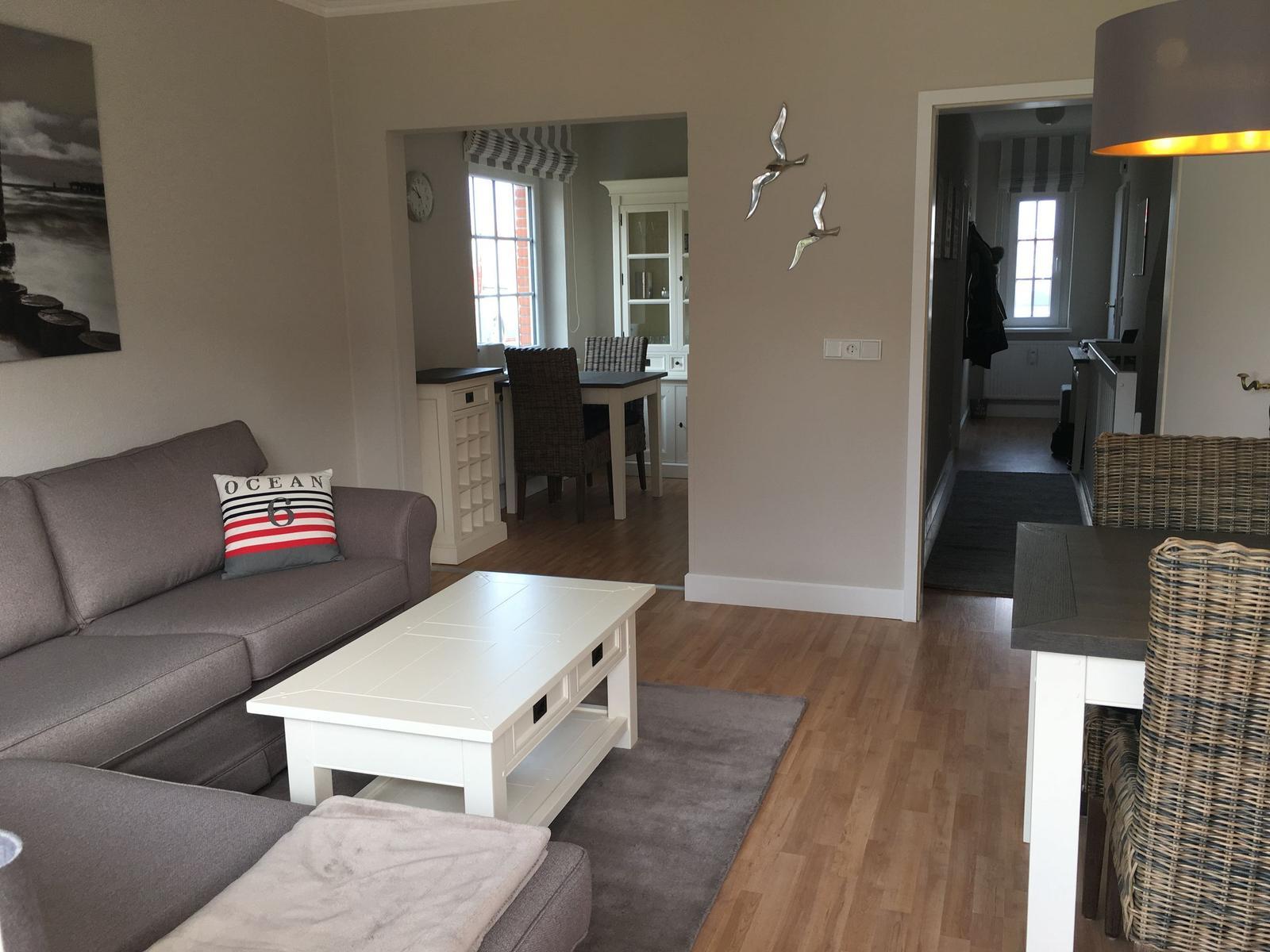 Wohnzimmer mit Sofa, Couchtisch und Blick in Essbereich.