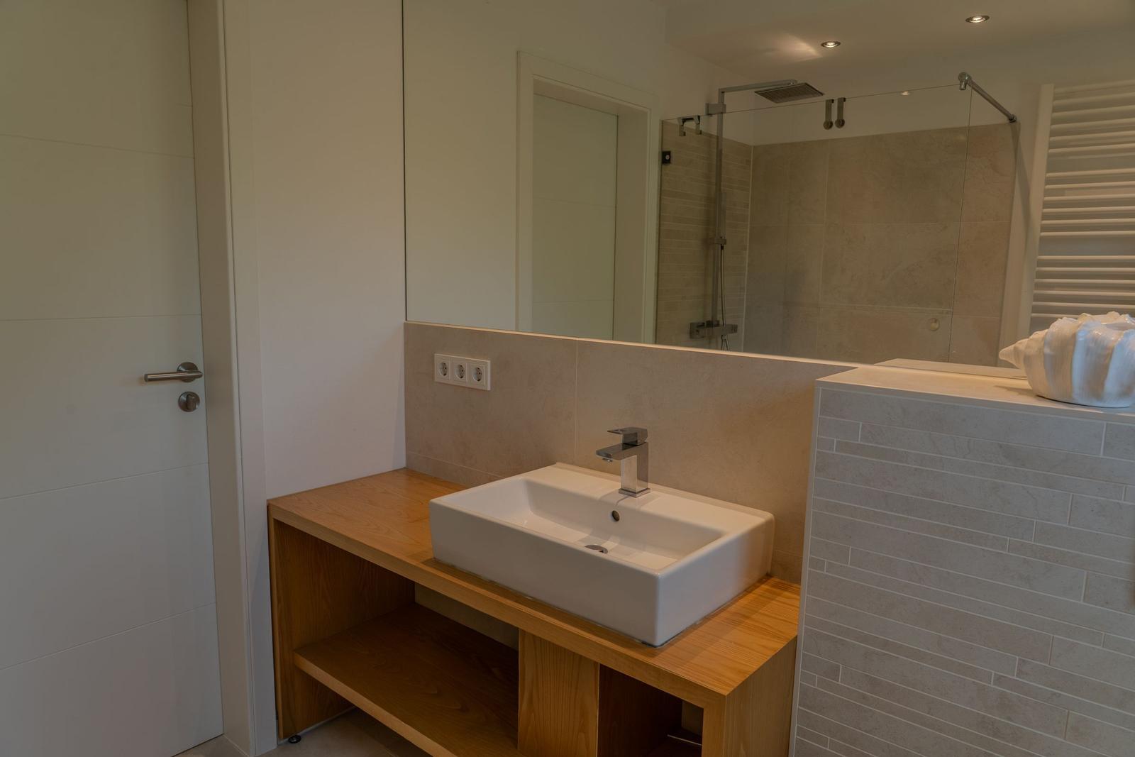 Bad mit Waschbecken auf Holzkonsole und Dusche mit Glaswand