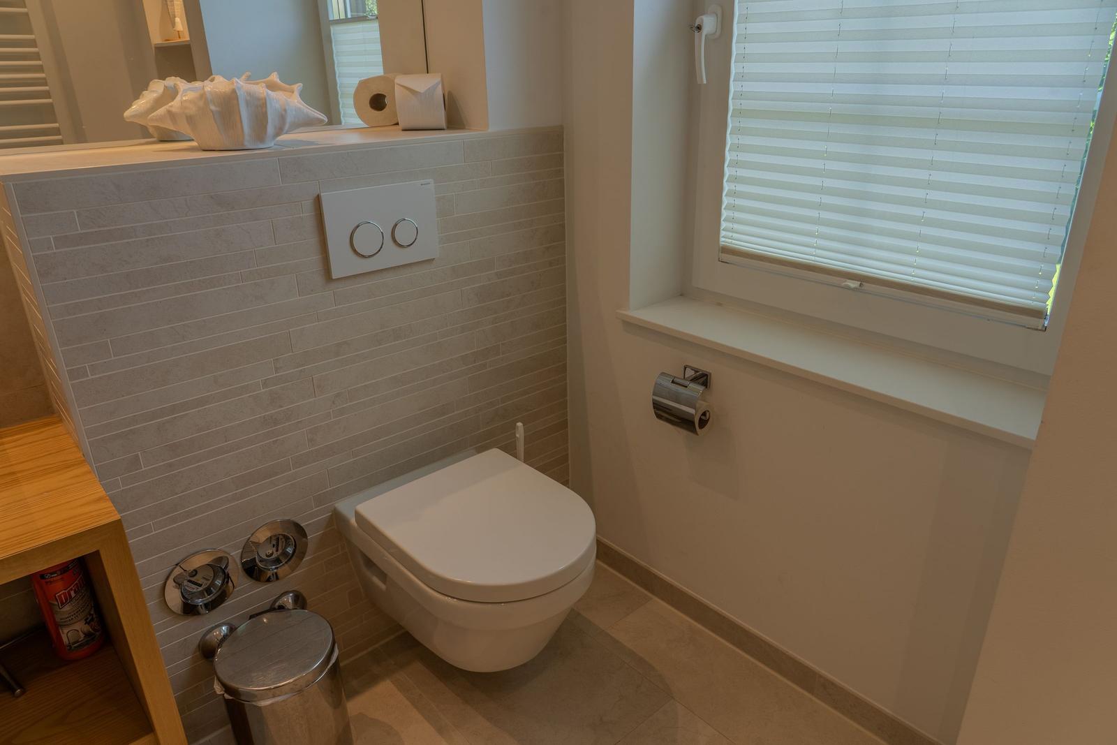 Toilette mit Fenster und moderner Wandverkleidung.