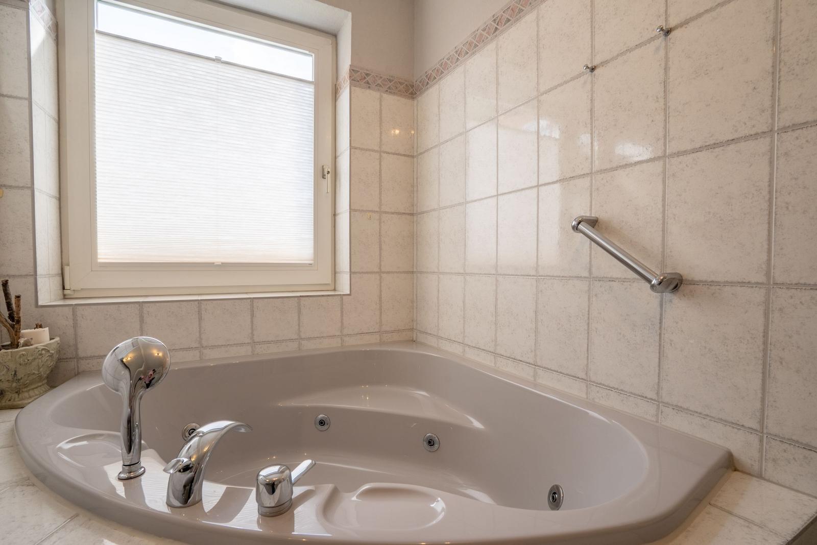Eine Badewanne mit Duschkopf und Fenster