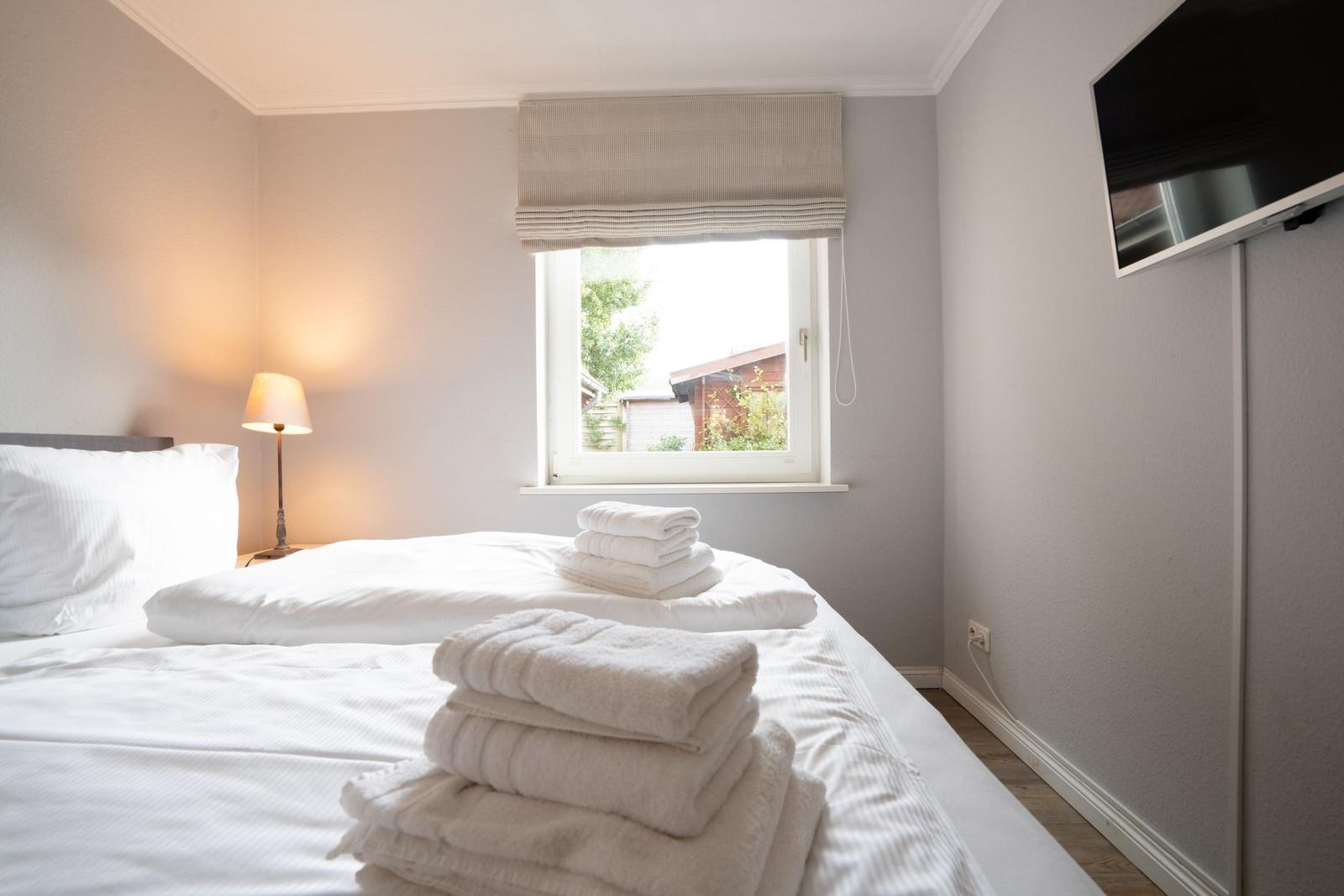 Schlafzimmer mit Bett, Fenster und Fernseher.