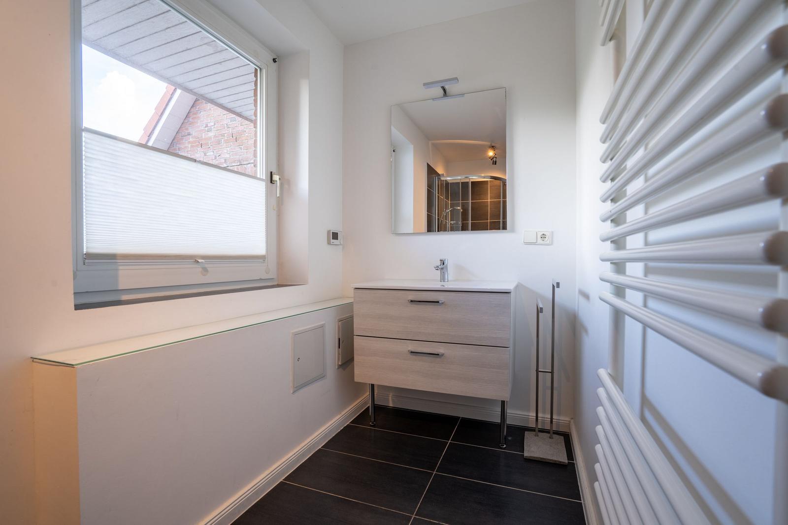 Badezimmer mit Waschbecken, Spiegel und Fenster.