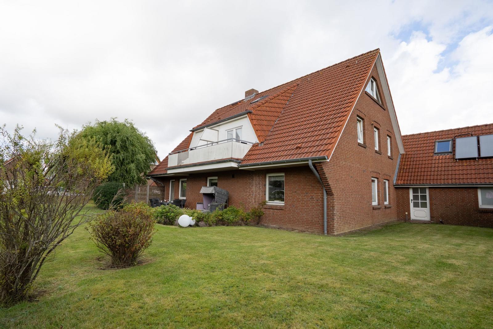 Rotes Ziegelhaus mit Balkon und Garten. Solaranlage auf Dach.