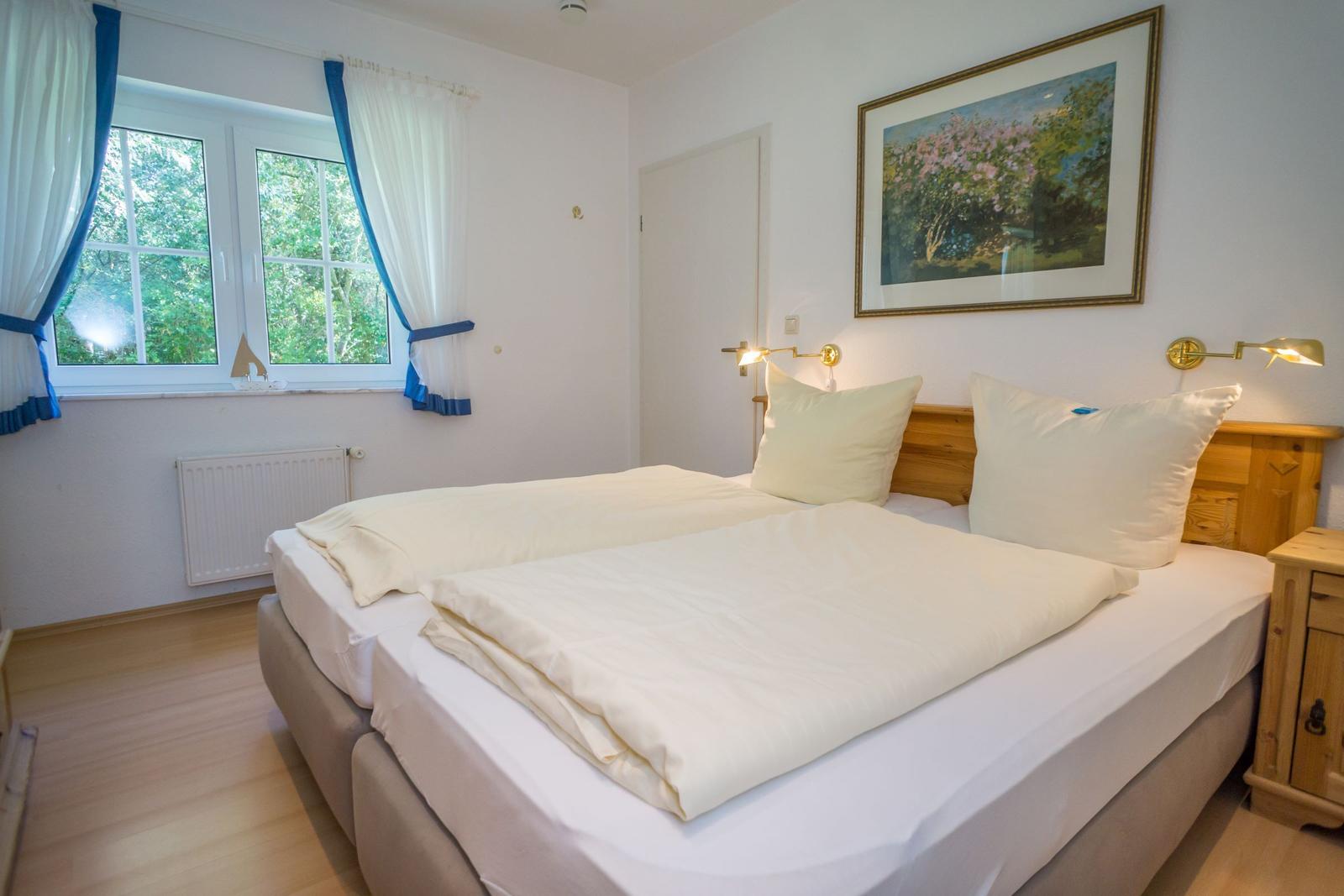 Schlafzimmer mit Doppelbett, Fenster und Wandbild.