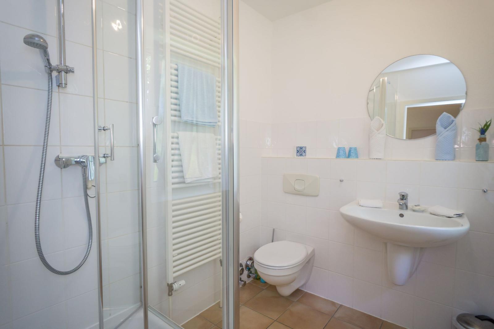 Badezimmer mit Dusche, Toilette und Waschbecken.