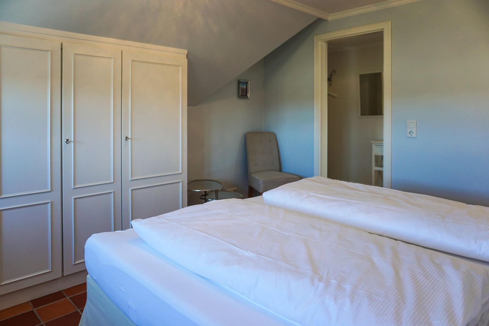 Zimmer mit Doppelbett, Kleiderschrank und Sessel