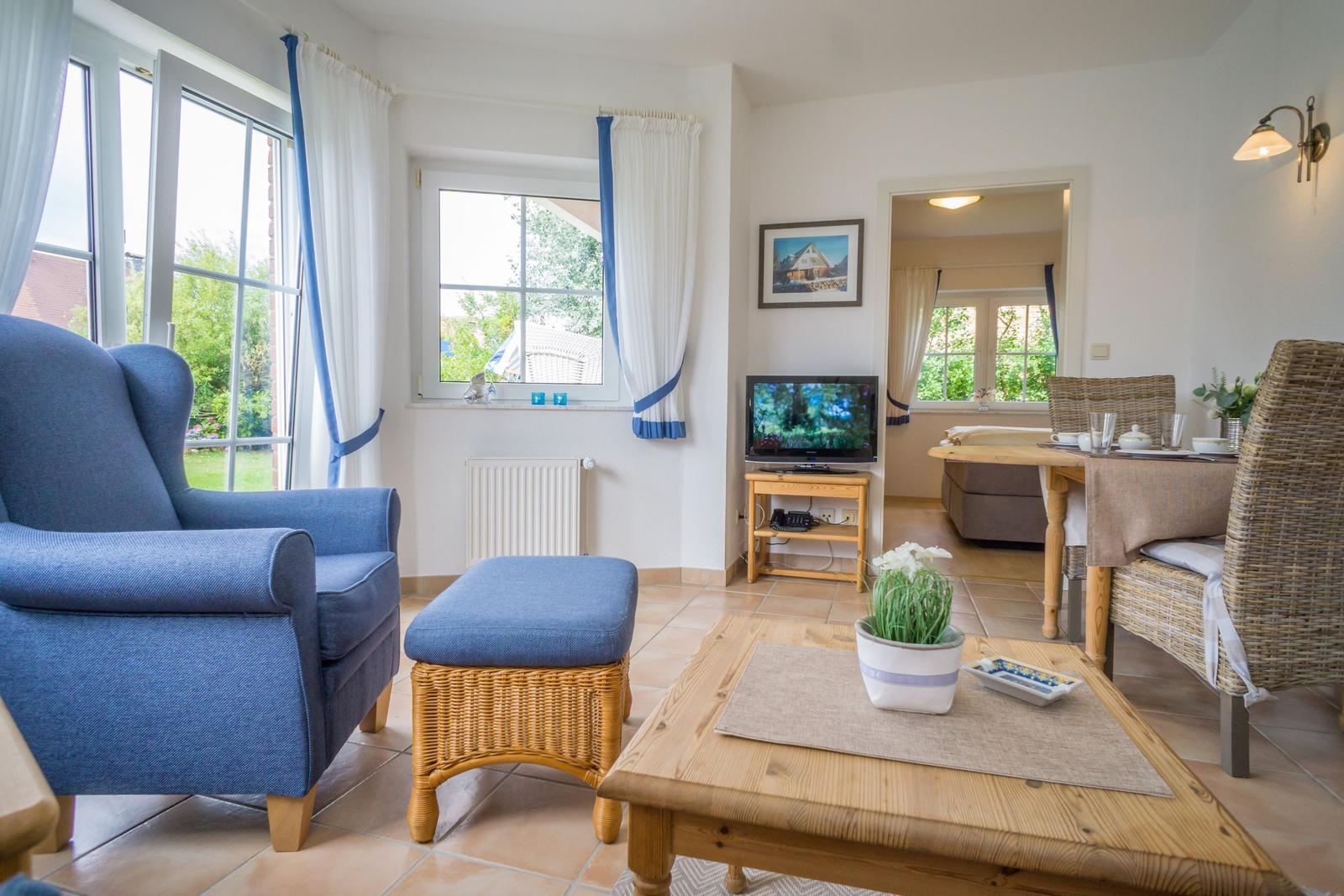 Living room with blue armchair, wooden table, and garden view.