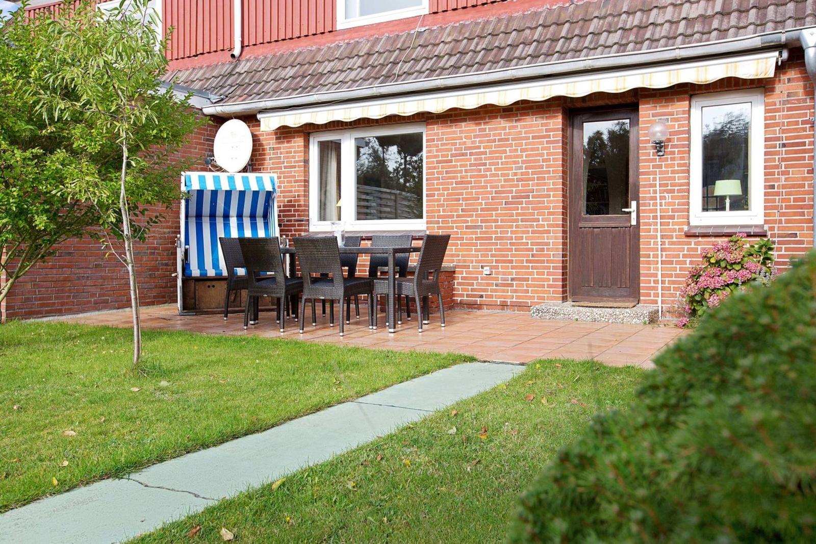 Red brick house with terrace, table, chairs, and beach chair.