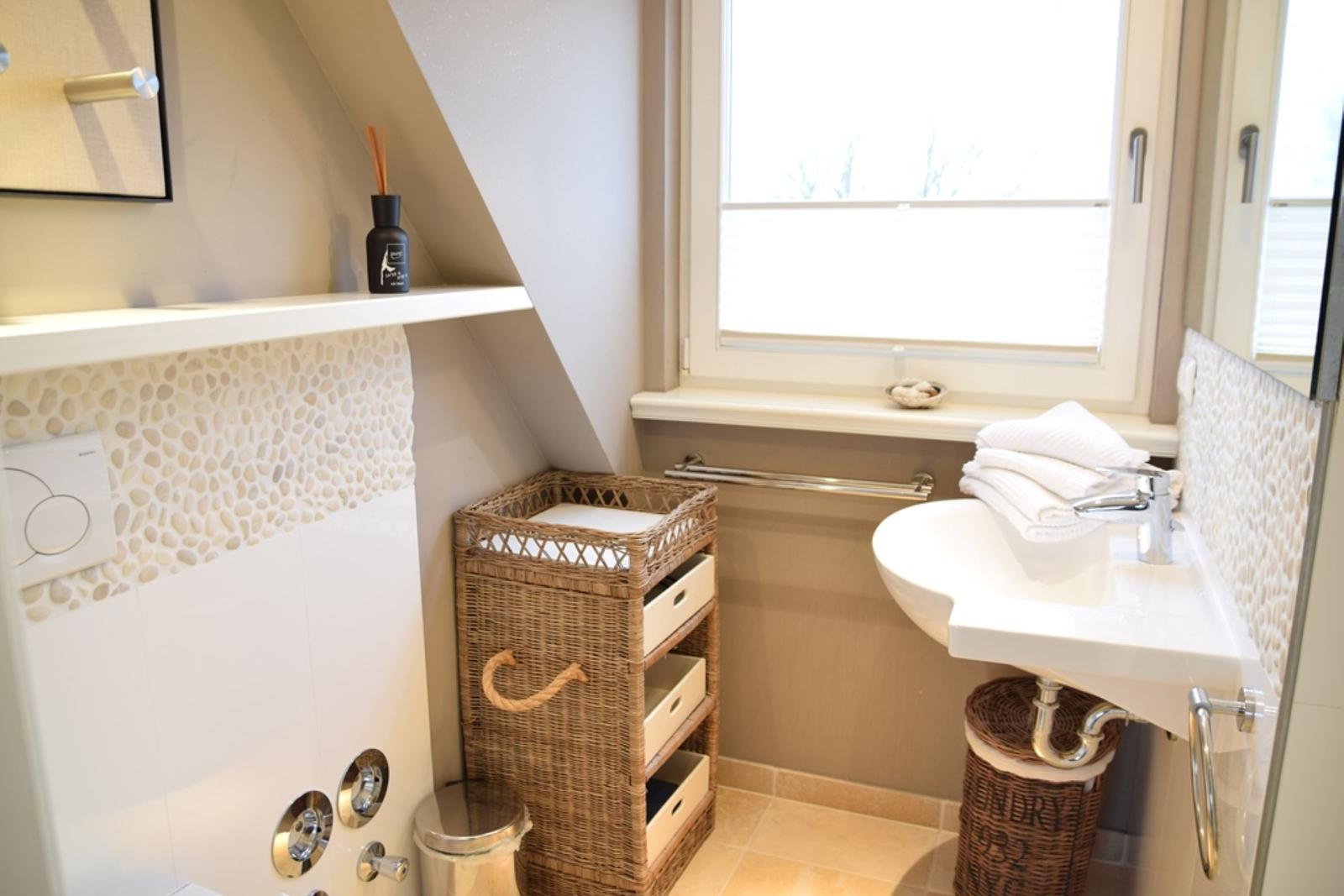 Badezimmer mit Waschbecken, Dusche und Fenster.