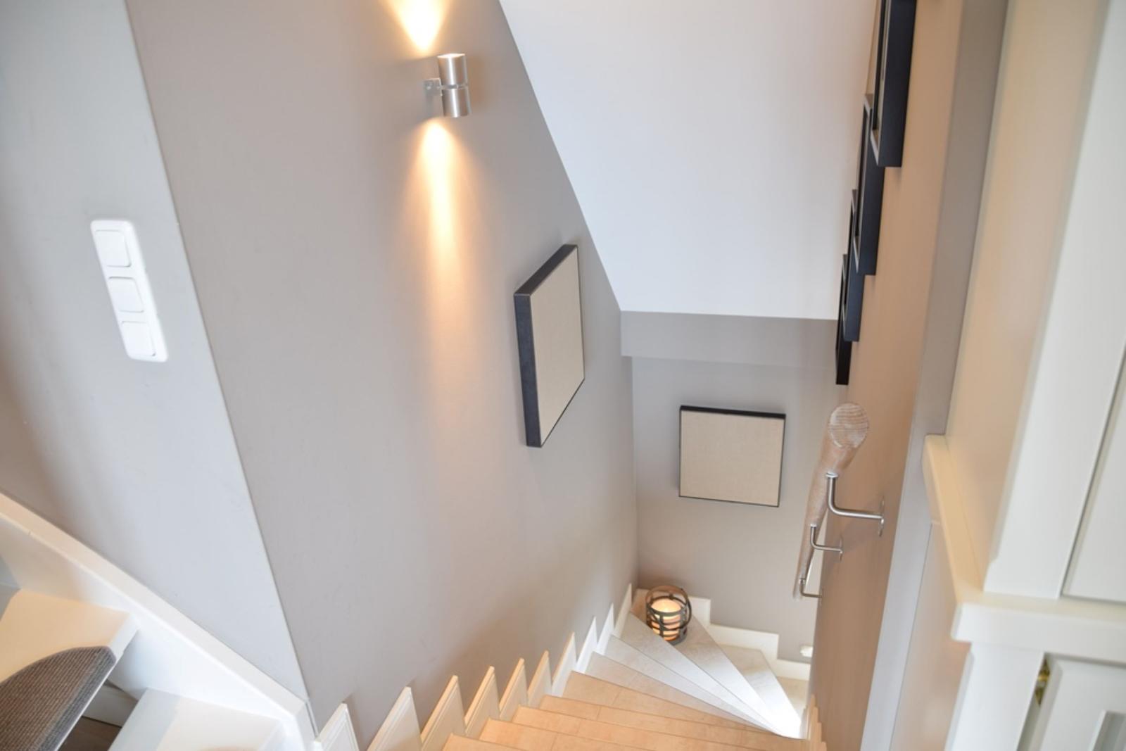 Helle Treppe mit moderner Beleuchtung und Wanddekoration.