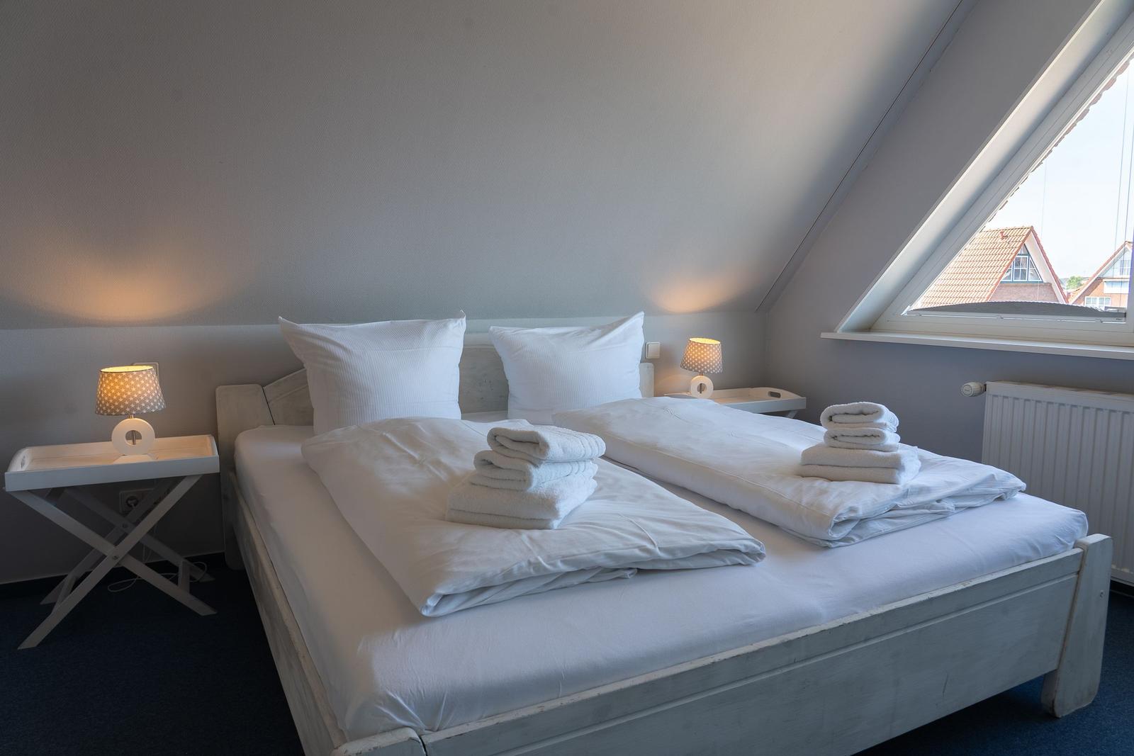 Schlafzimmer mit Doppelbett, zwei Nachttischen und Dachfenster.