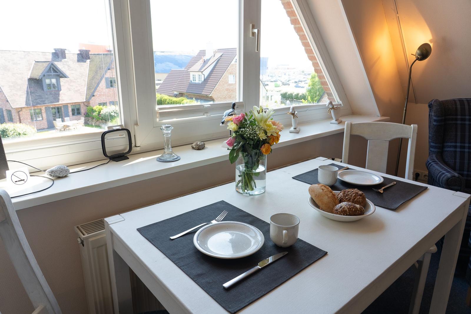 Tisch mit Platz für zwei, Blumen und Blick auf Dächer.