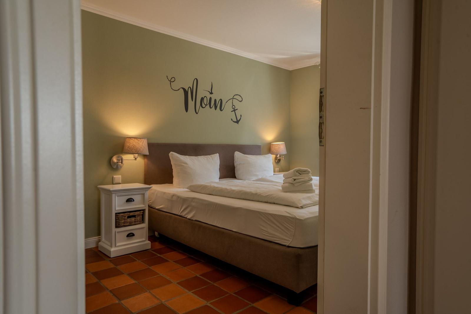 Bedroom with bed, nightstand, and wall decoration.