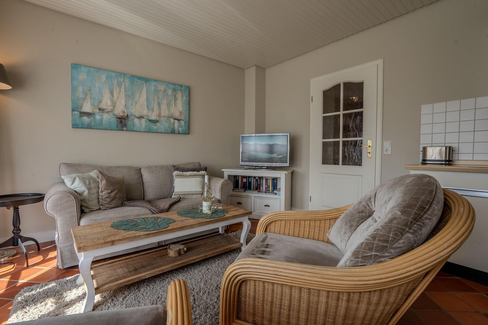Living room with sofa, armchair, and TV. Wall art with sailboats.