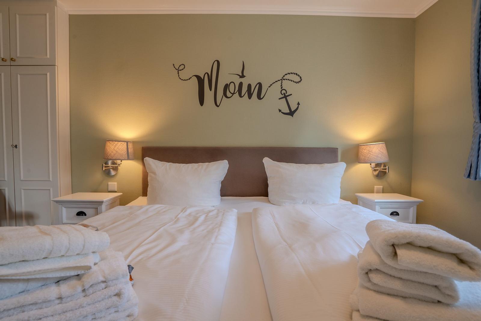 Bedroom with double bed, nightstands, and wall decor.